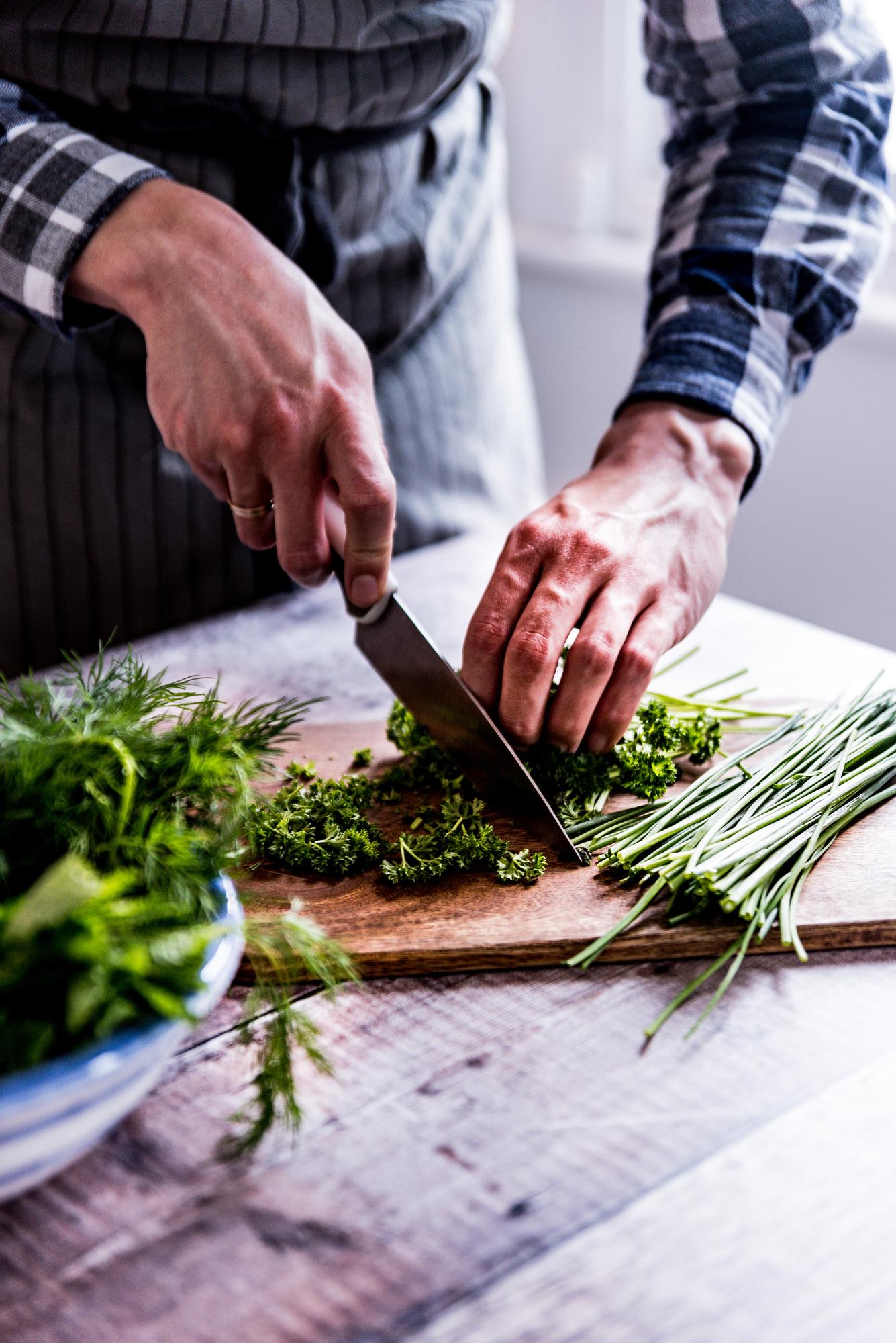 Chef hands chopping herbs near window